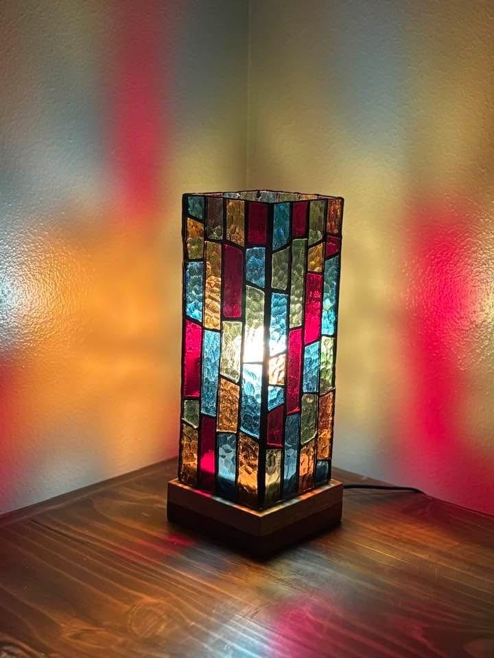 An illuminated stained glass tower casting colorful light across a wall